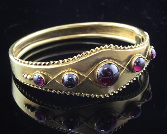 A Victorian gold and graduated cabochon almandine garnet hinged bangle, gross 16 grams.